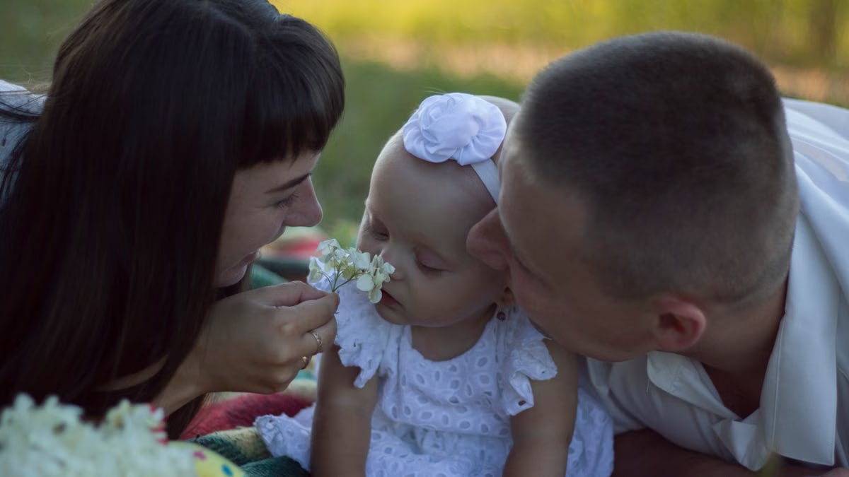 A loving family moment with parents and baby at a sunny outdoor picnic.