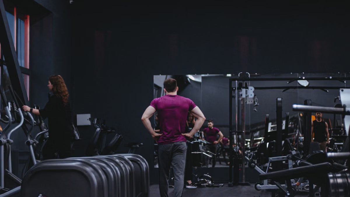 Man in a gym with fitness equipment, highlighting a healthy lifestyle.